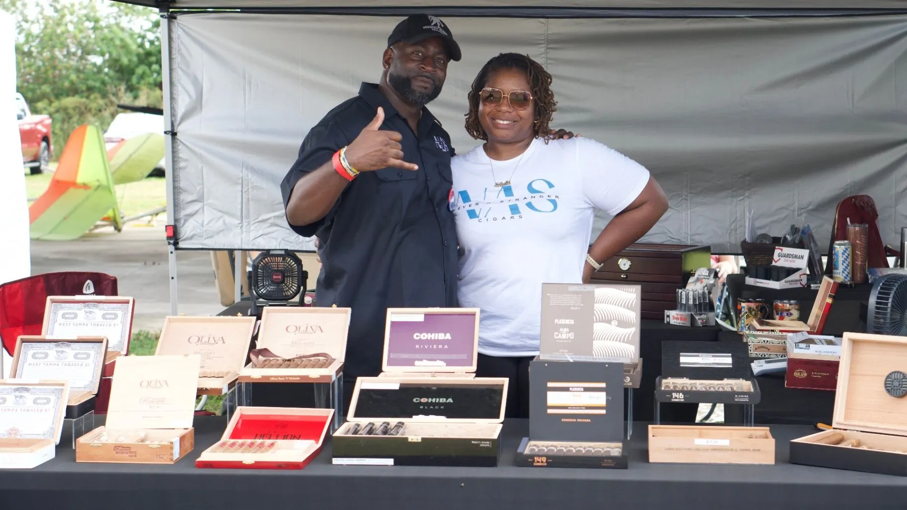 Two people stand behind a local vendor table filled with boxed products.