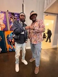 Two people stand together in a gallery or cultural exhibit space.